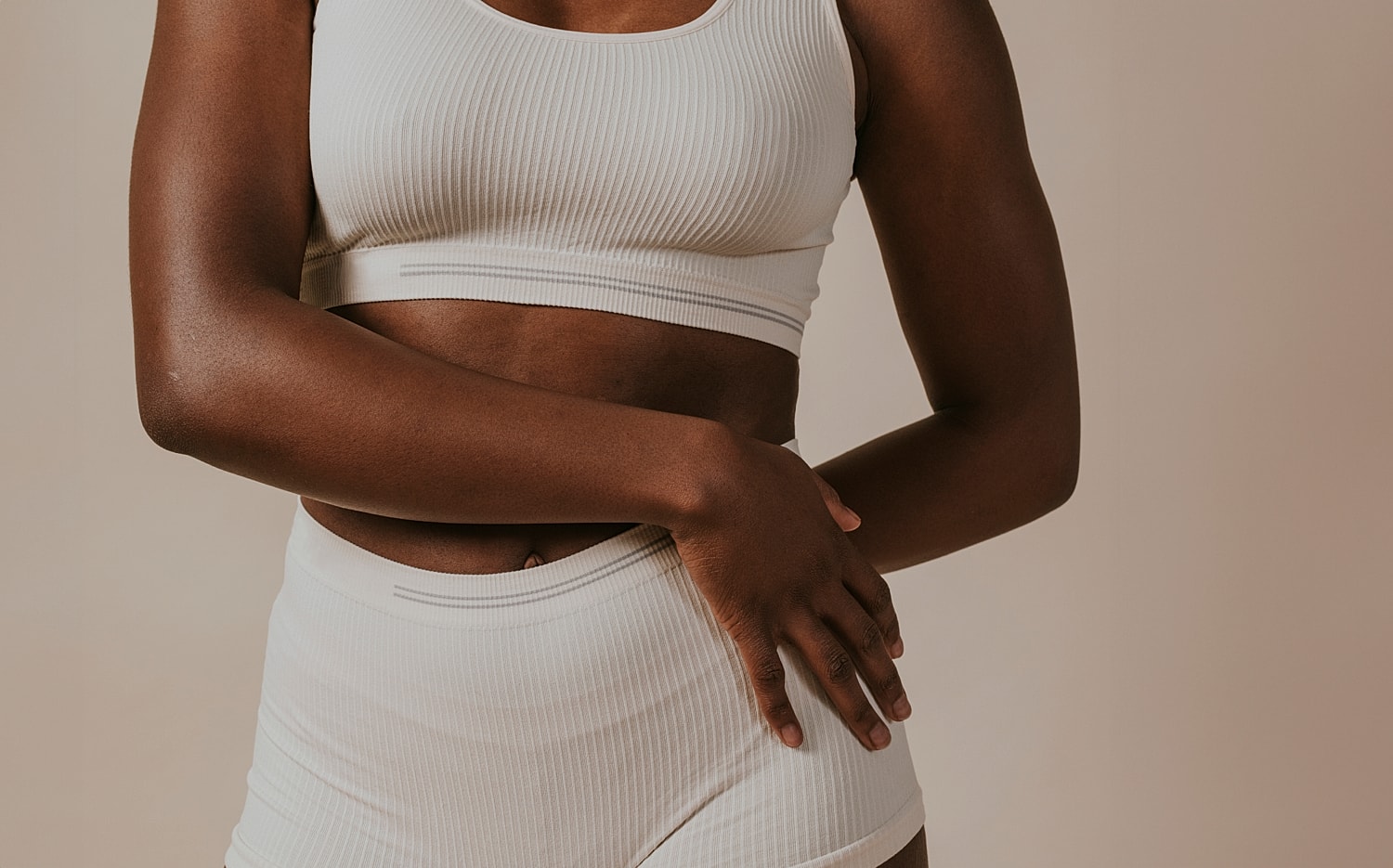 Woman in light activewear against a neutral background.