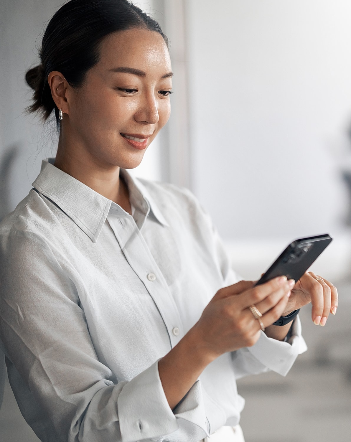 Woman smiling while using a smartphone.