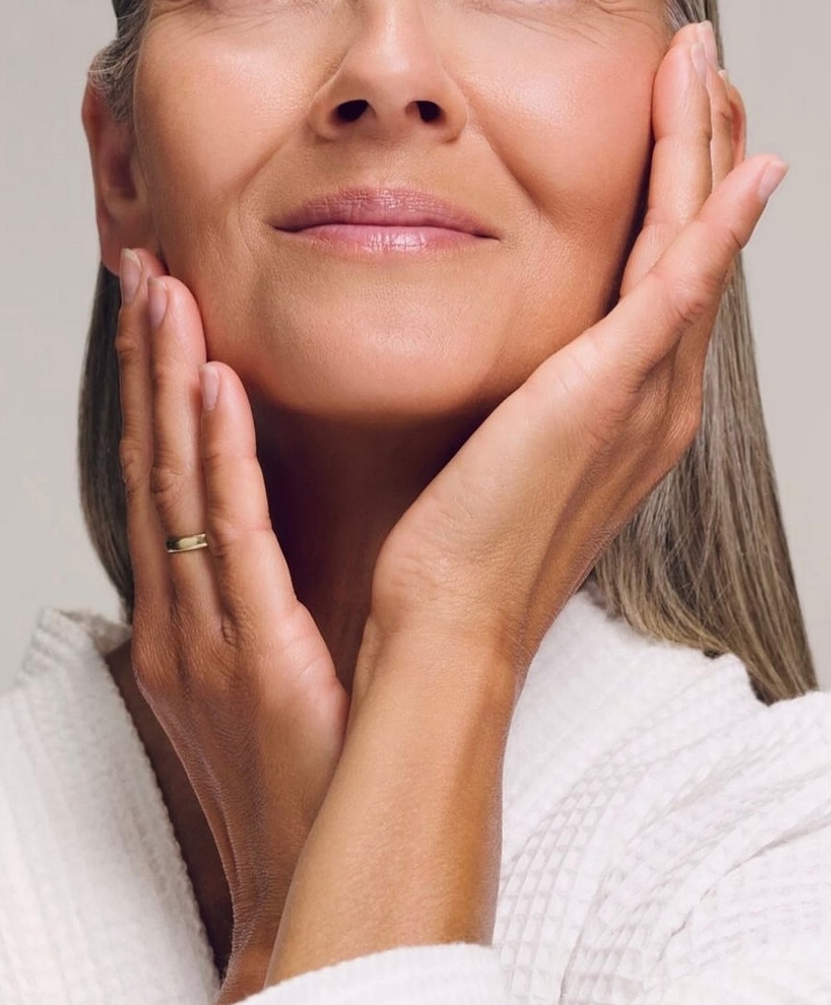 Woman gently touching her face, smiling softly.