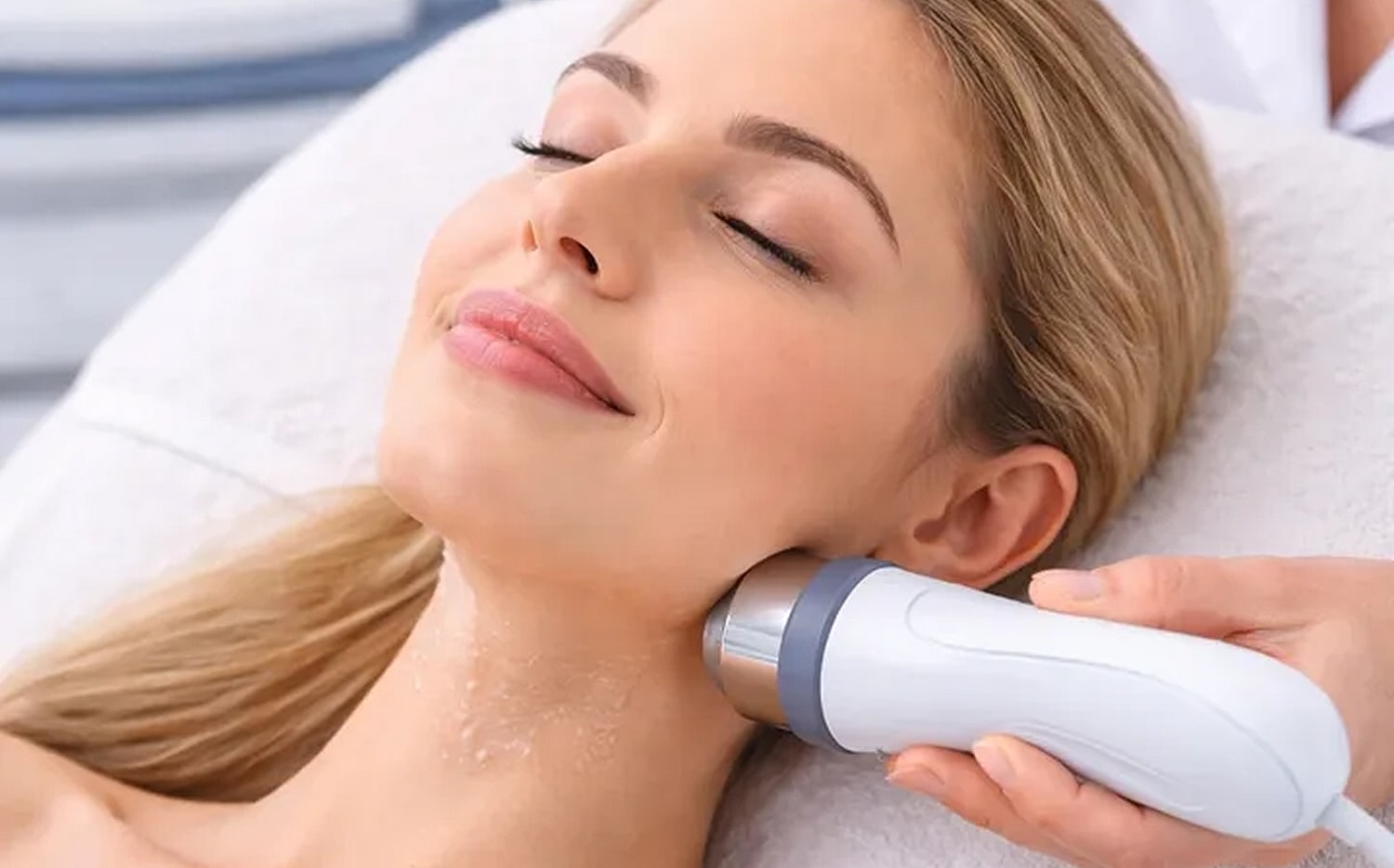 Woman receiving facial treatment with device.