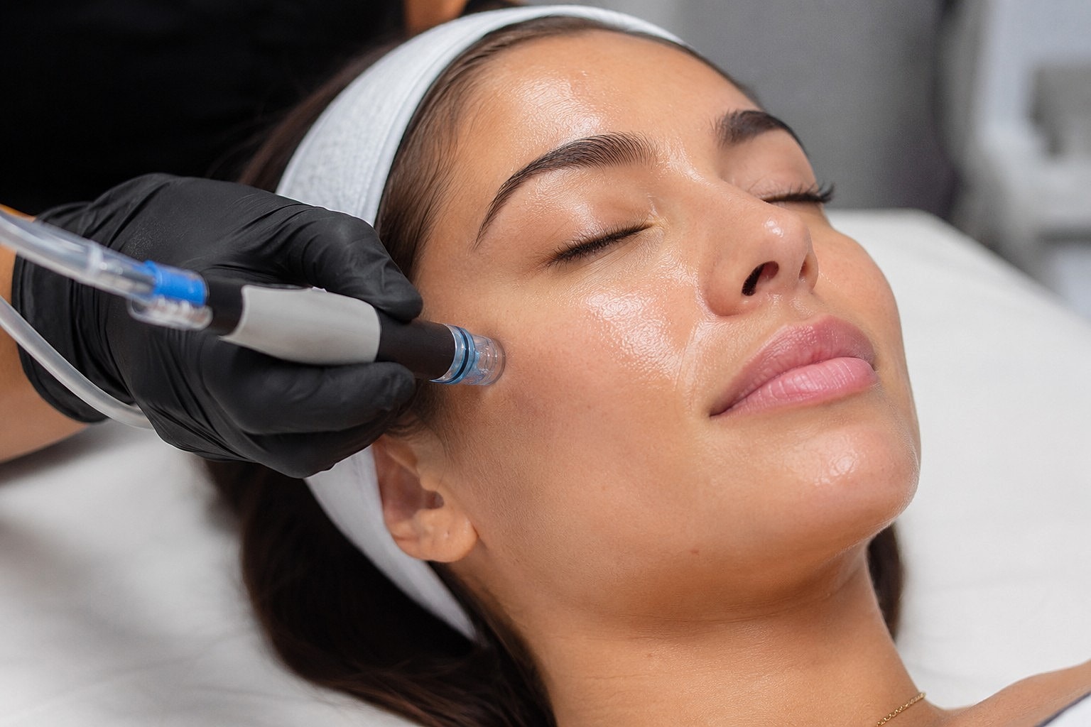 Woman receiving facial treatment with microdermabrasion device.