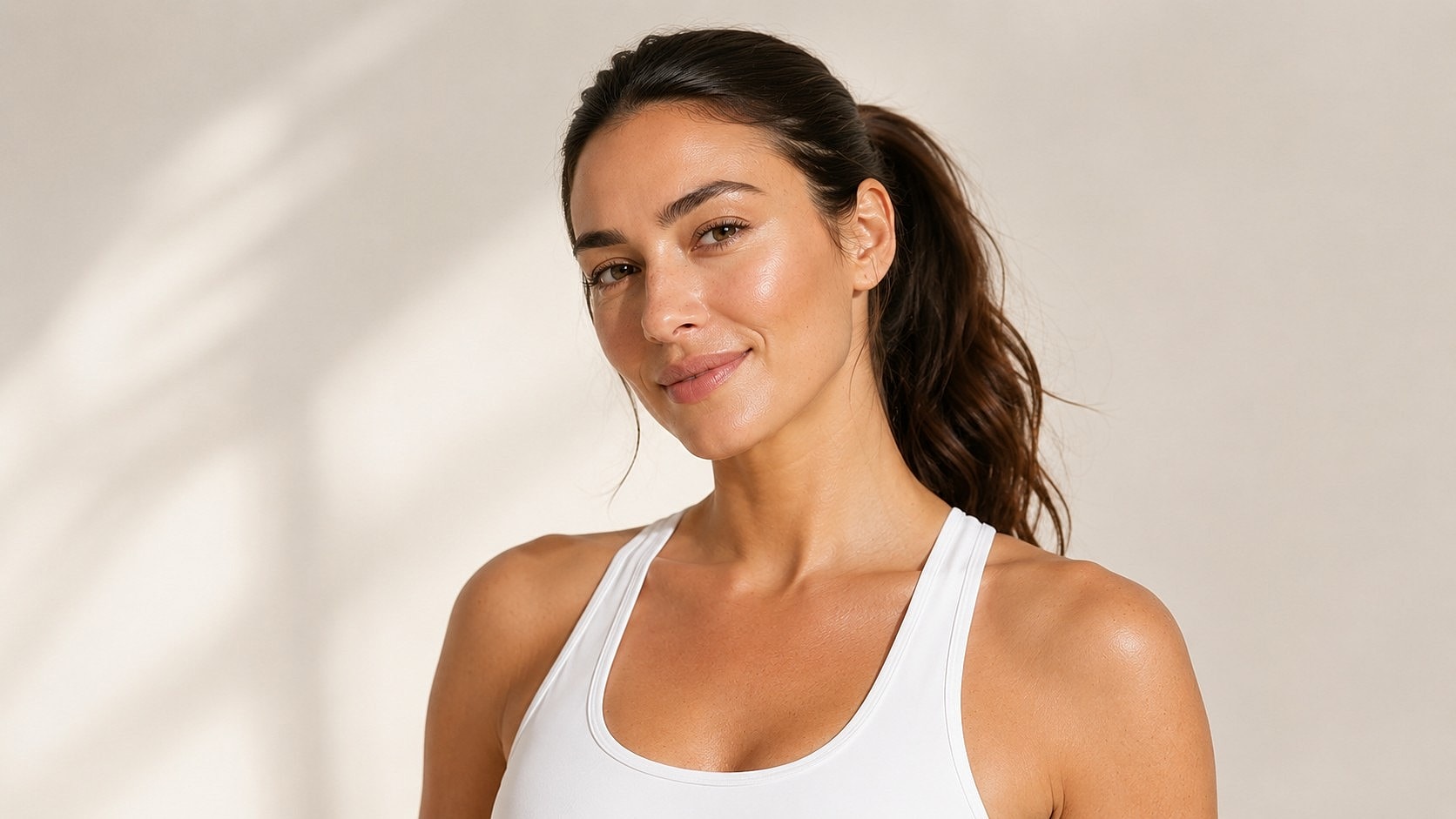 Smiling woman in athletic attire against neutral background.